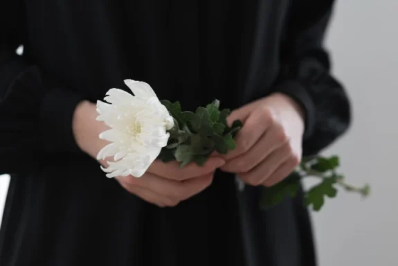 svartklädd person håller vit blommma