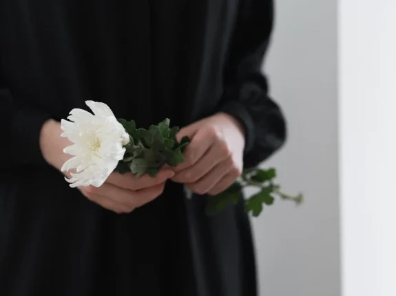 svartklädd person håller vit blommma