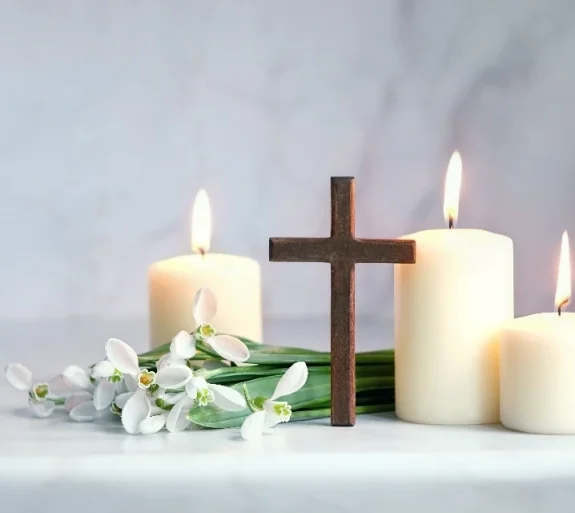 stilleben, litet träkors, tända ljus och vita blommor