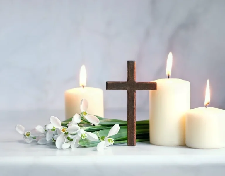stilleben, litet träkors, tända ljus och vita blommor