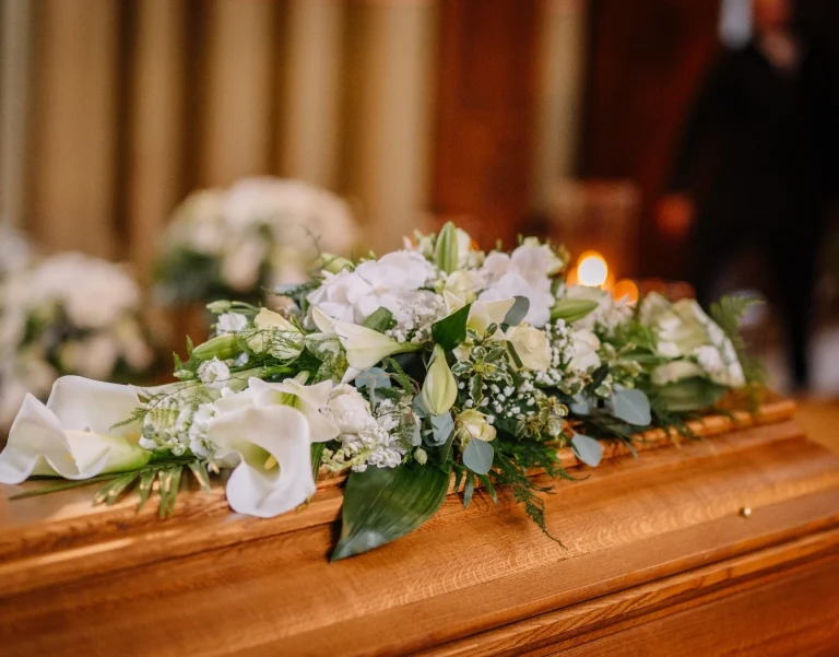 vitt blomsterarrangemang på kista, planera begravning
